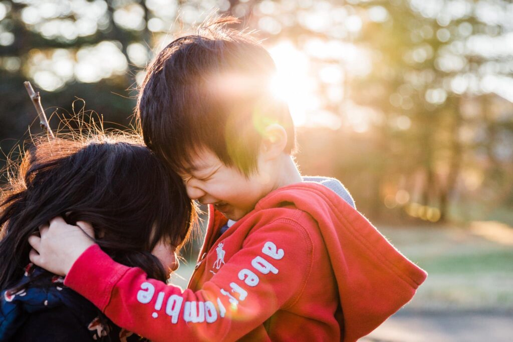 Two children hugging each other in the sun, bathed in warm Nashville light.