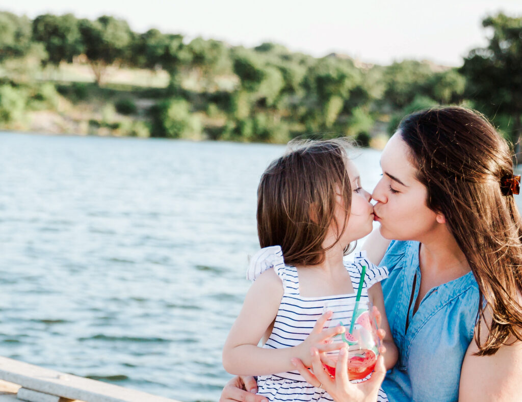 A mother and daughter kissing on a dock near a lake in Austin, Texas.