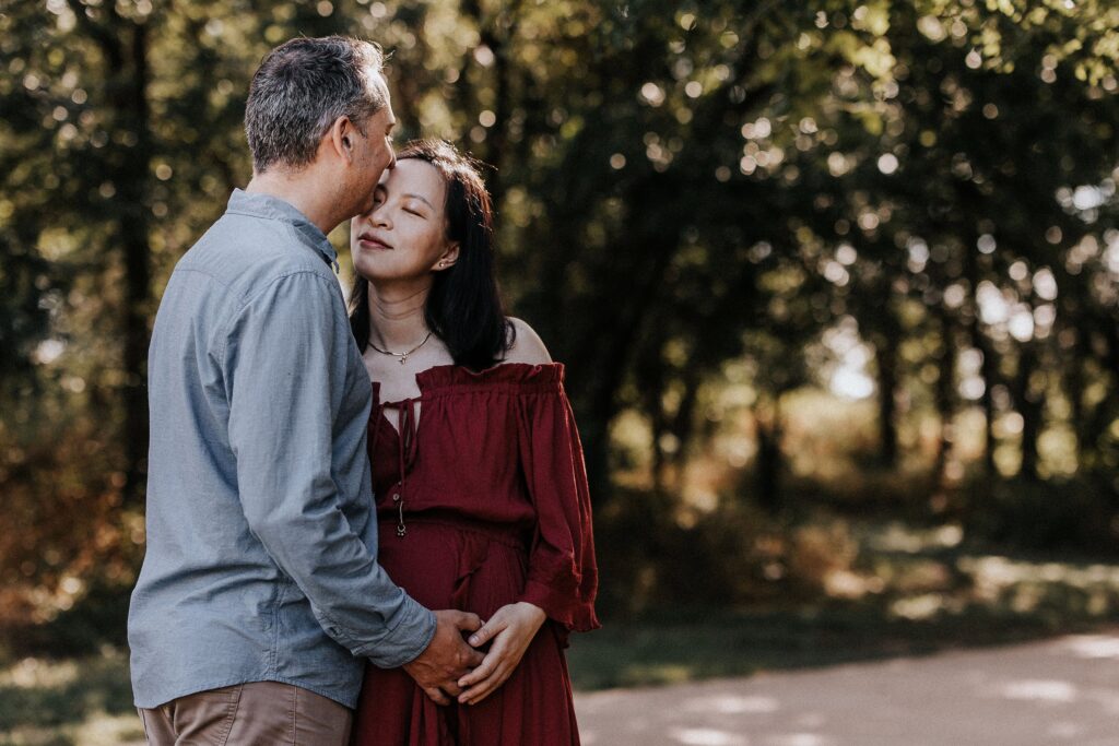 A couple embracing in the woods during their maternity session.