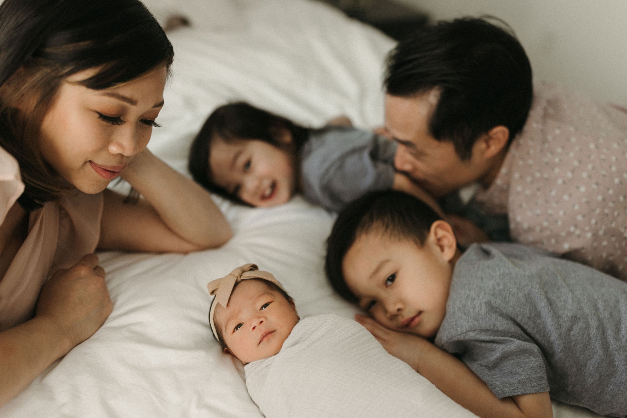 A family laying on a bed with a newborn baby.