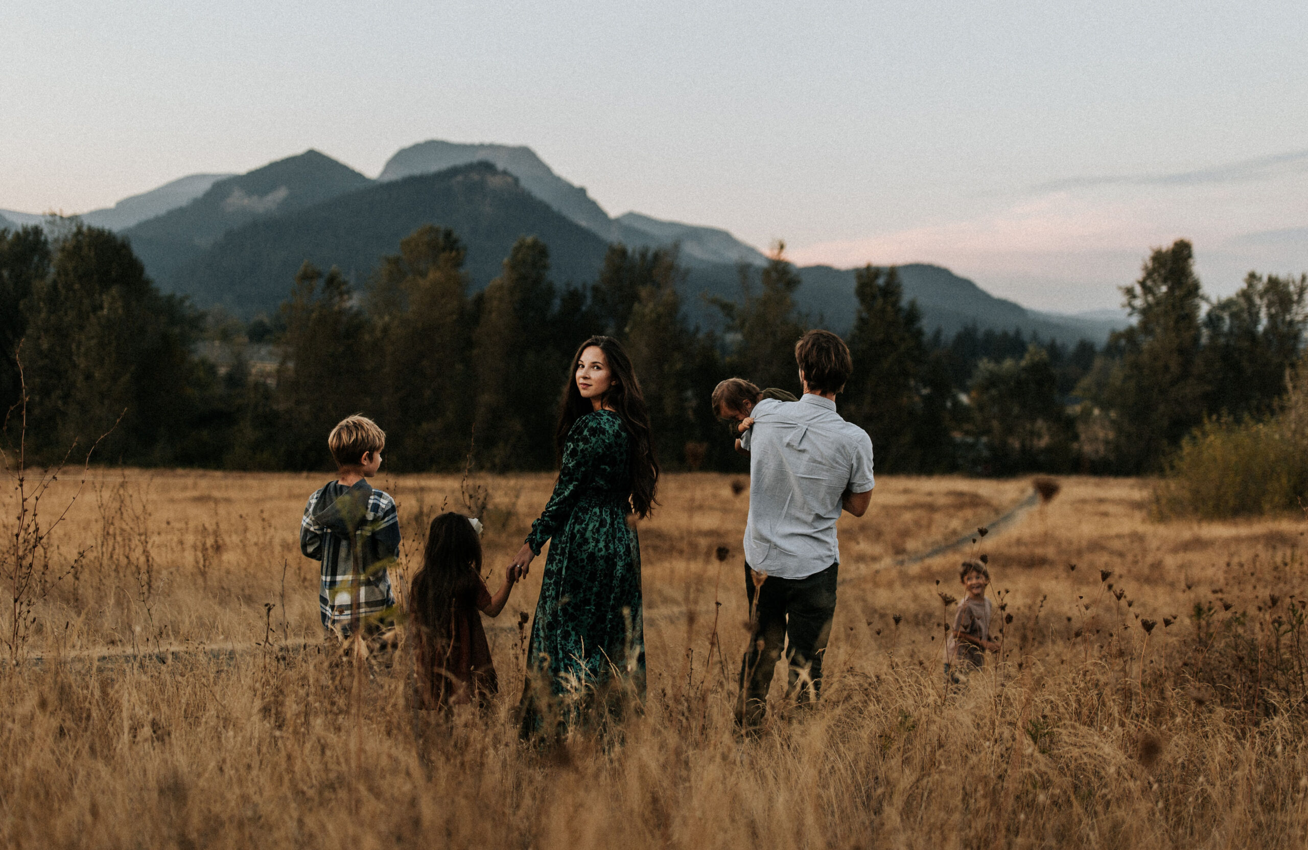 A family walks through a field with mountains in the background in Portland Oregon.