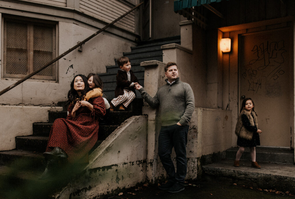 A family enjoys a family photo session on the steps of an old house in Downtown Portland.