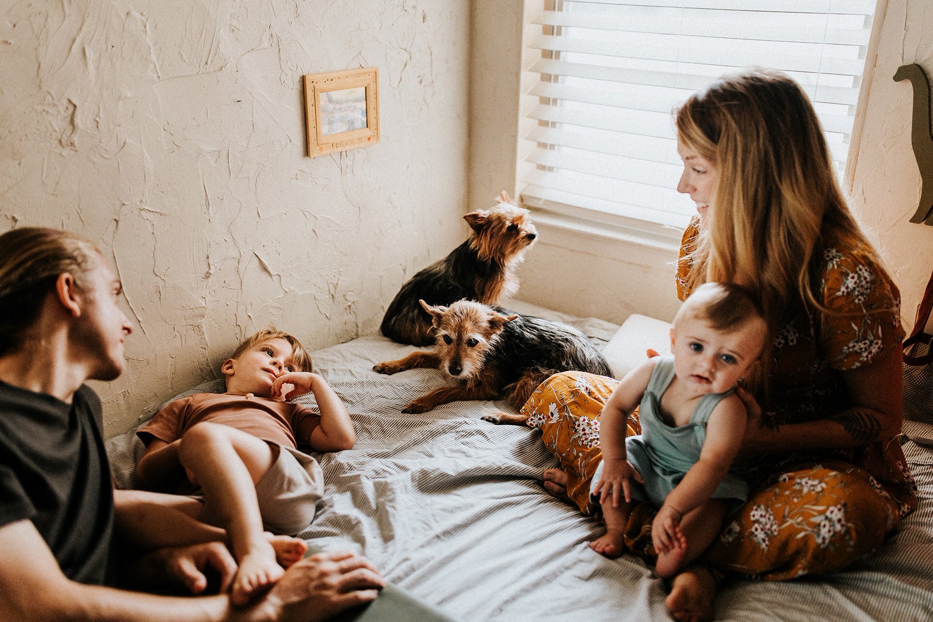 In a cozy bedroom in Portland, Oregon, a loving family gathers for a heartwarming fall photo. The bed is filled with the joyful presence of two children and their beloved dog.
