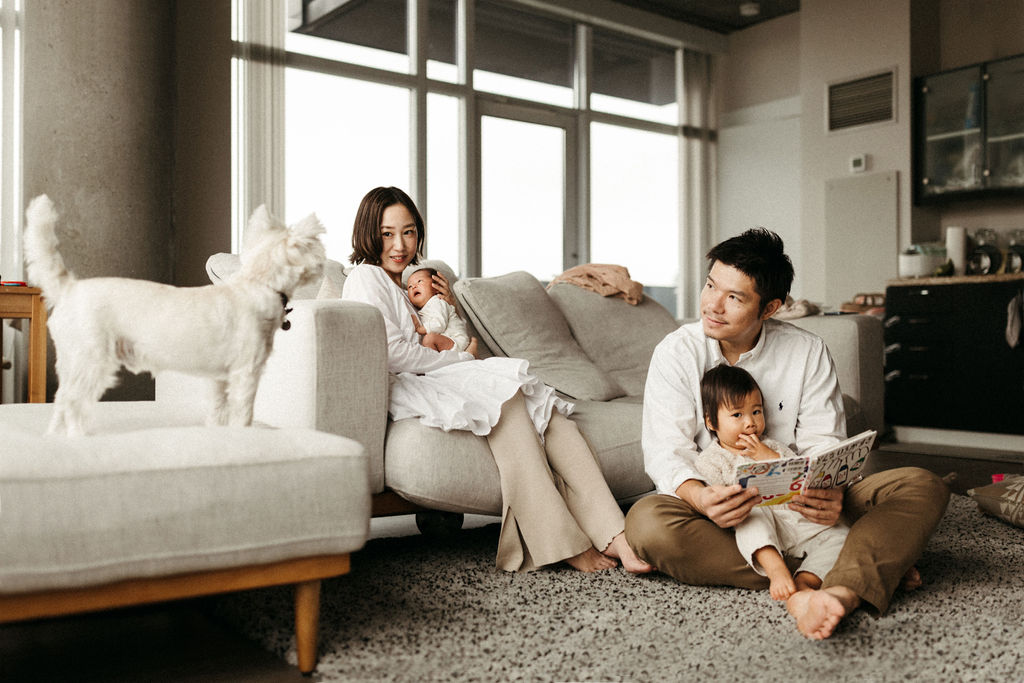 A family is sitting in their apartment reading a book.